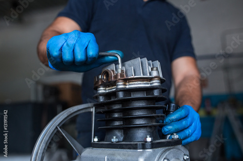 Mechanic fixing a compressor engine photo