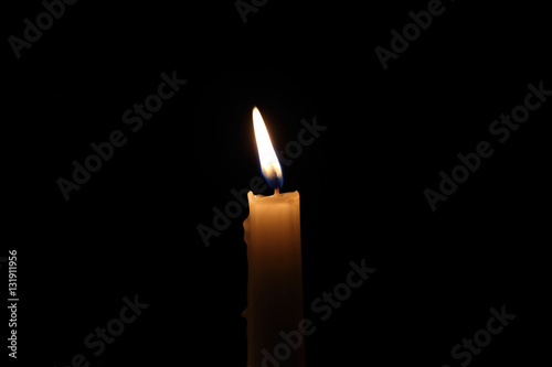 lit candle on the black background