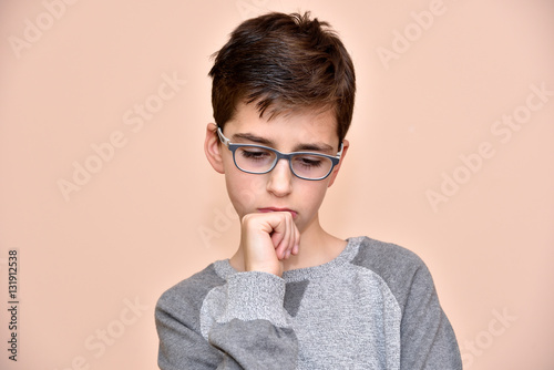 Thoughtful cute young boy with glasses 