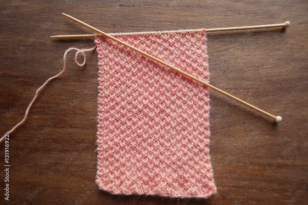 Knitting a pink pastel wool scarf with moss stitch pattern Knitting a pink pastel wool scarf with moss stitch pattern