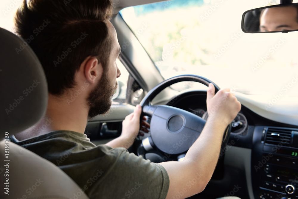 Young successful driver keeping hands on steering wheel