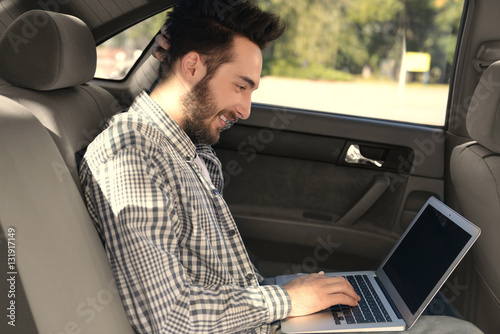 Successful young man using laptop while sitting in car © Africa Studio