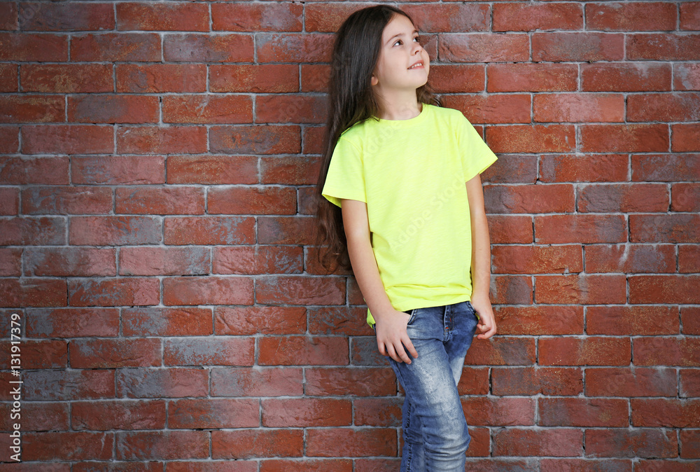 Little girl in blank color t-shirt standing against brick wall Little girl in blank color t-shirt standing against brick wall