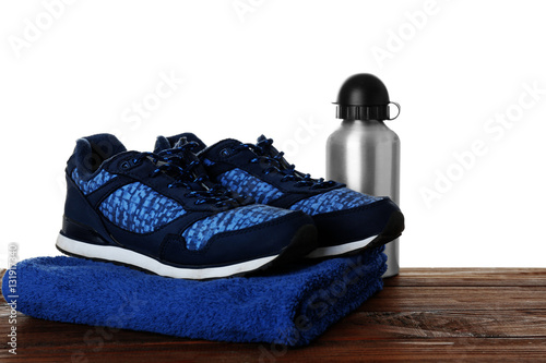 Sport shoes, towel and bottle on table