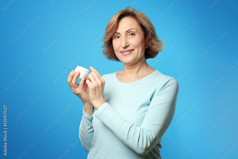 Gorgeous senior woman applying anti-aging cream on blue background Gorgeous senior woman applying anti-aging cream on blue background