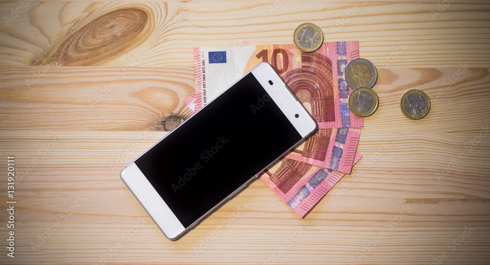 Smartphone und Geldscheine auf Holzuntergrund Smartphone und Geldscheine auf Holzuntergrund