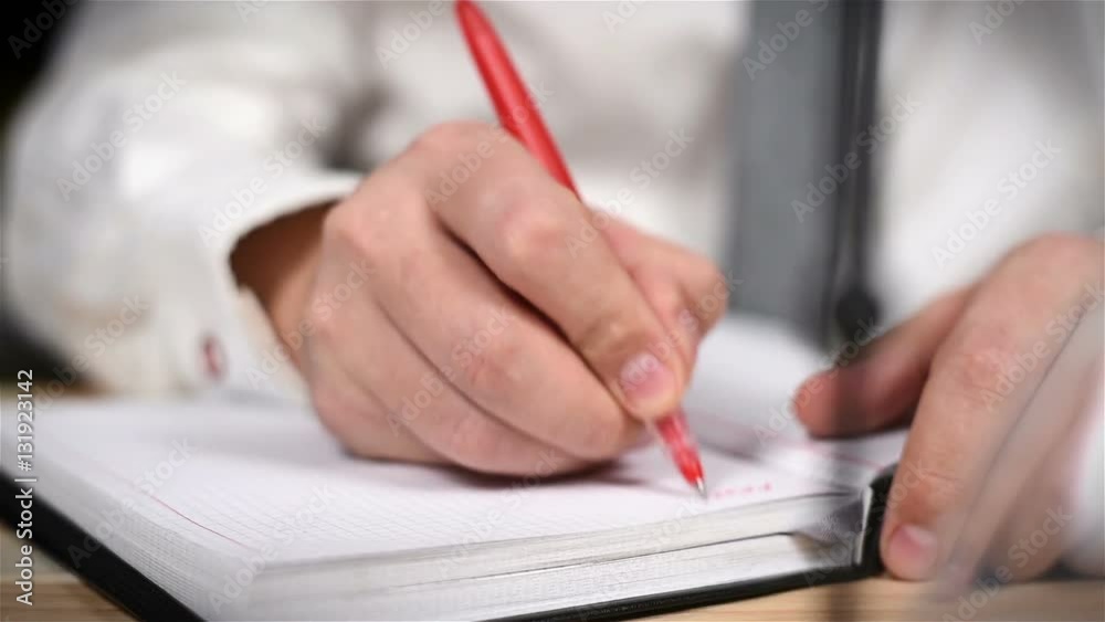 Trader Hand Taking Stock Exchange Statistics In Diary. Close Up Trader Hand Taking Stock Exchange Statistics In Diary. Close Up