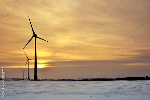 Windmills for electric power production. Winter landscape at sunset time. Poland.