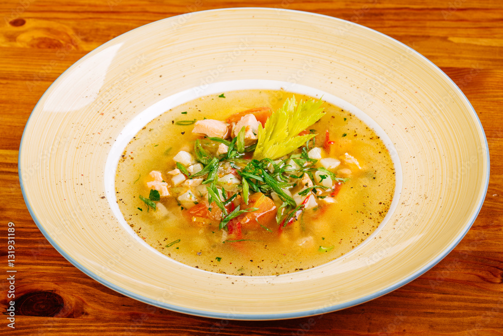 soup with fish and vegetables served on a white round plate soup with fish and vegetables served on a white round plate