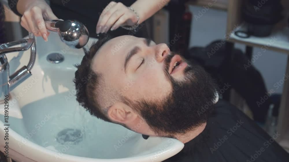 Young hipster man having his hair washed at a hair salon. 4K Young hipster man having his hair washed at a hair salon. 4K