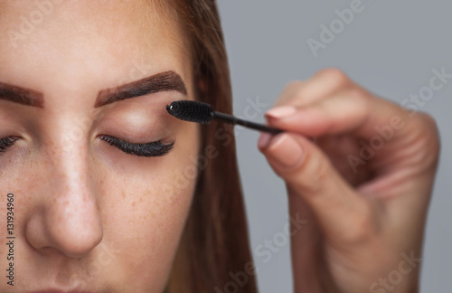 Master makeup corrects and gives shape to pull out with forceps previously painted with henna eyebrows in a beauty salon. Professional care for face.