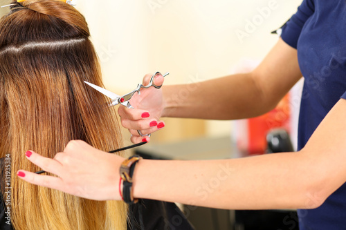 Female hairdresser hold in hand between fingers lock of blonde h