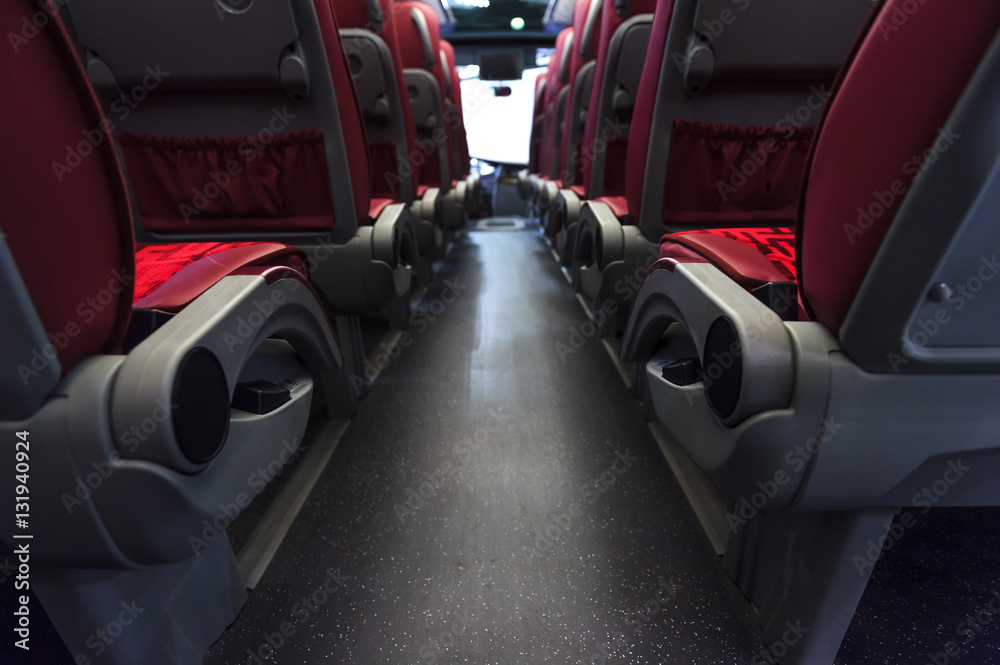 Bus seats in row with red leather, textile coating, wooden armrests and mounts for safety belts, rear view, modern comfortable tourist transport interior, selective focus Bus seats in row with red leather, textile coating, wooden armrests and mounts for safety belts, rear view, modern comfortable tourist transport interior, selective focus