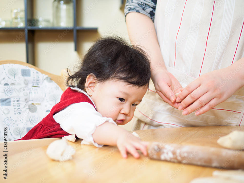 Fototapeta premium Adorable baby girl making gyoza with mom