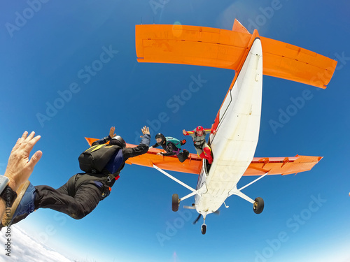 A group of skydivers friends jumping from the orange plane