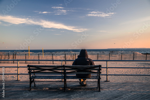 Woman sitting on bench at Coney Island Boardwalk