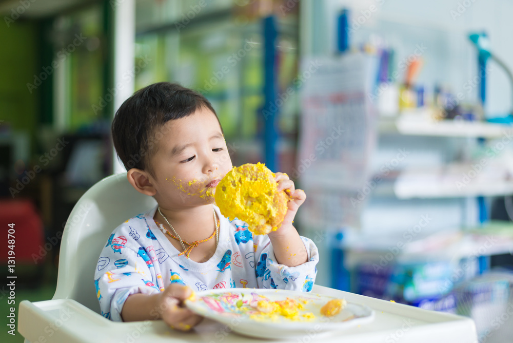 Asian kid eating birthday cake with cream on face. Asian kid eating birthday cake with cream on face.