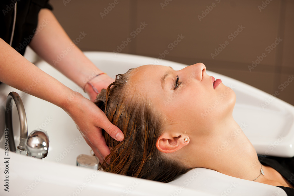 Obraz premium Hair stylist at work - hairdresser washing hair to the customer