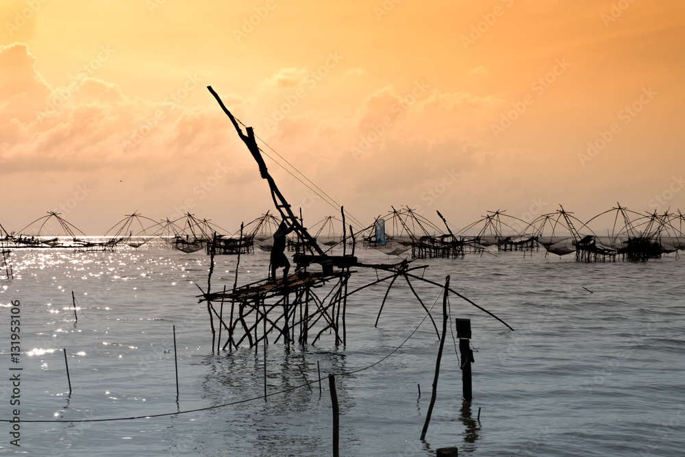 Silhouette of traditional fishing method using a bamboo square dip net with sunrise sky background,livelihoods of fishermen at Pakpra, Phattalung in Thailand