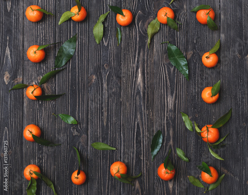 Fototapeta Naklejka Na Ścianę i Meble -  Frame made of freshly picked orange tangerines on a dark textured wooden background, top view
