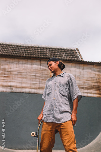 Skateboarder stands with skateboard in skatepark