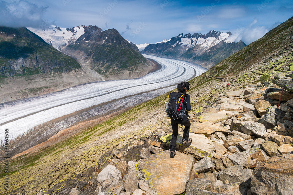 Fototapeta premium Girl walking on spectacular mountain scenery, Aletsch glacier in background Alps, Switzerland.