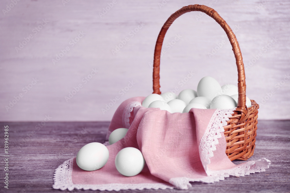 Raw eggs in basket on wooden table