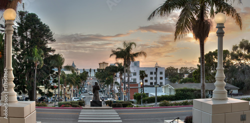 Father statue overlooking Downtown Ventura as dusk glows in sky.
