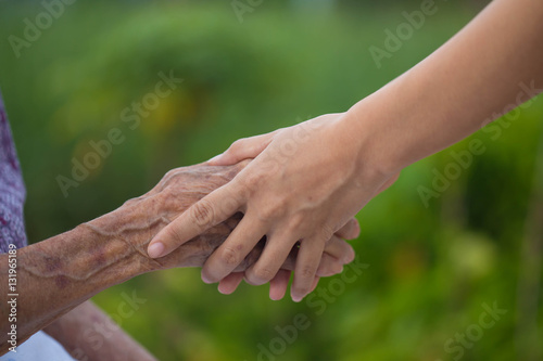 Old and young holding hands on light background, closeup © patcharaporn1984