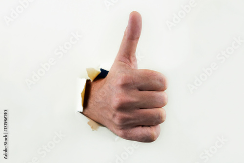 Hand with thumb up through paper