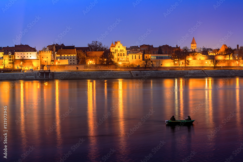Panorama of Torun Old Town at night with colorful reflection in Vistula river. Poland, Europe.
