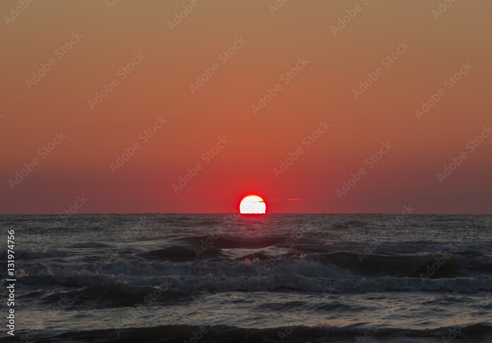 Fiery sunrise at Italian beach. Summer season. Emilia Romagna region. Adriatic sea. Italy