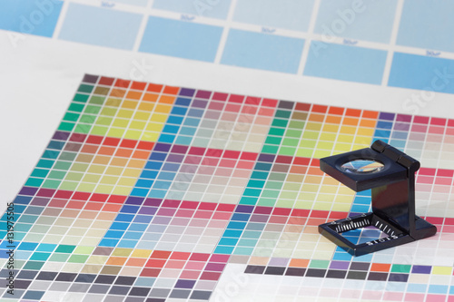 Magnifier or printer's loupe sits on a colorful CMYK test sheet