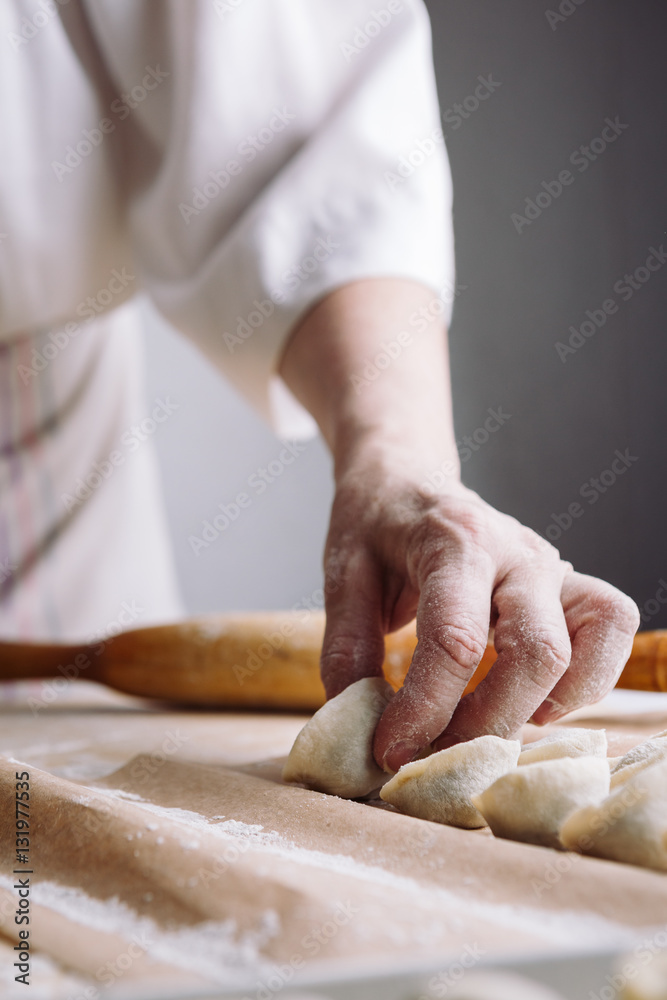 Close up view of woman folds the raw dumplings on a sheet of parchment Close up view of woman folds the raw dumplings on a sheet of parchment