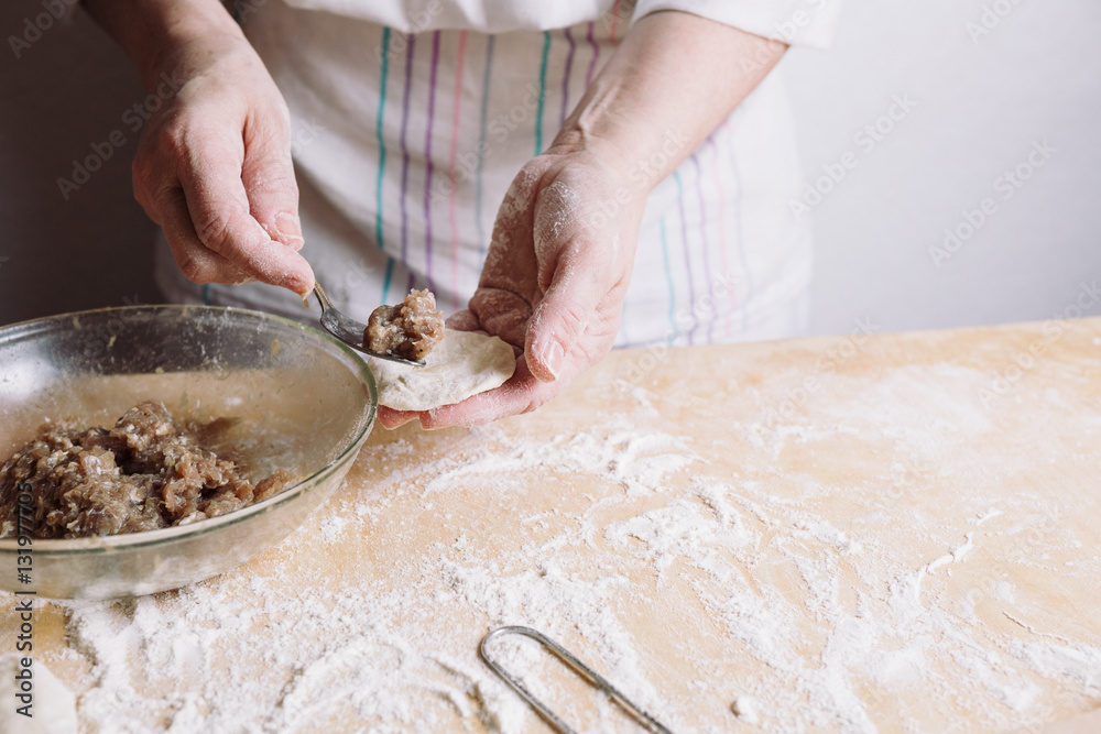 Front mid view of woman's hands making meat dumplings. Front mid view of woman's hands making meat dumplings.