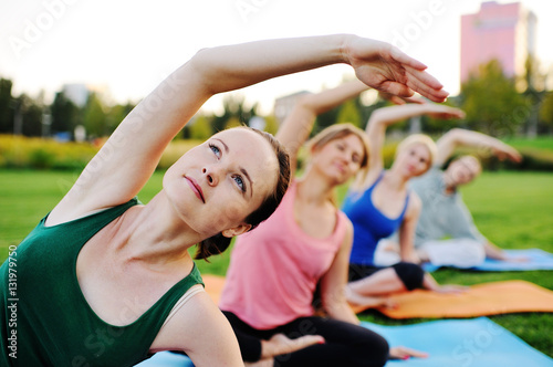 group of people doing yoga on the green with fresh grass outdoors. Healthy lifestyle photo