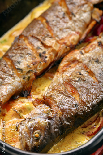 Baked fish with lemon sauce and vegetables in a pan