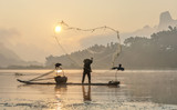 Cormorant fisherman throws a net with ancient bamboo boats at sunrise - Xingping, China