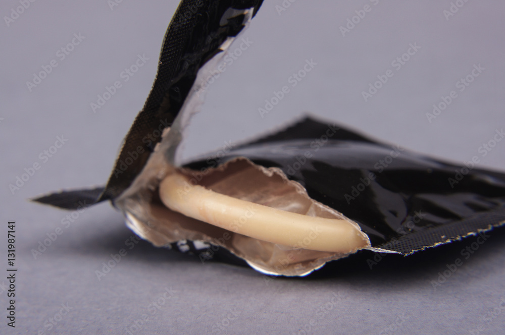 Condom in torn wrapper isolated on the gray background Stock Photo