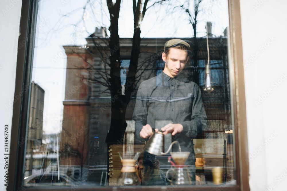 Man barista in window with glass pitcher
