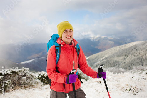 Girl with backpack walking on snow in the mountains.