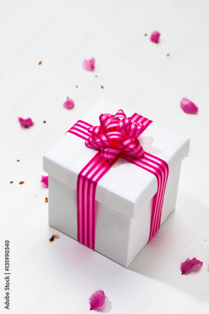 White gift box with pink ribbon and plum petal White gift box with pink ribbon and plum petal