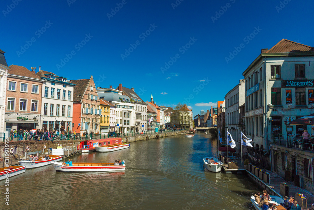 GHENT, Belgium - APRIL 10, 2016: View of old colorful traditional houses along the canal and boats in popular touristic destination Ghent, Belgium