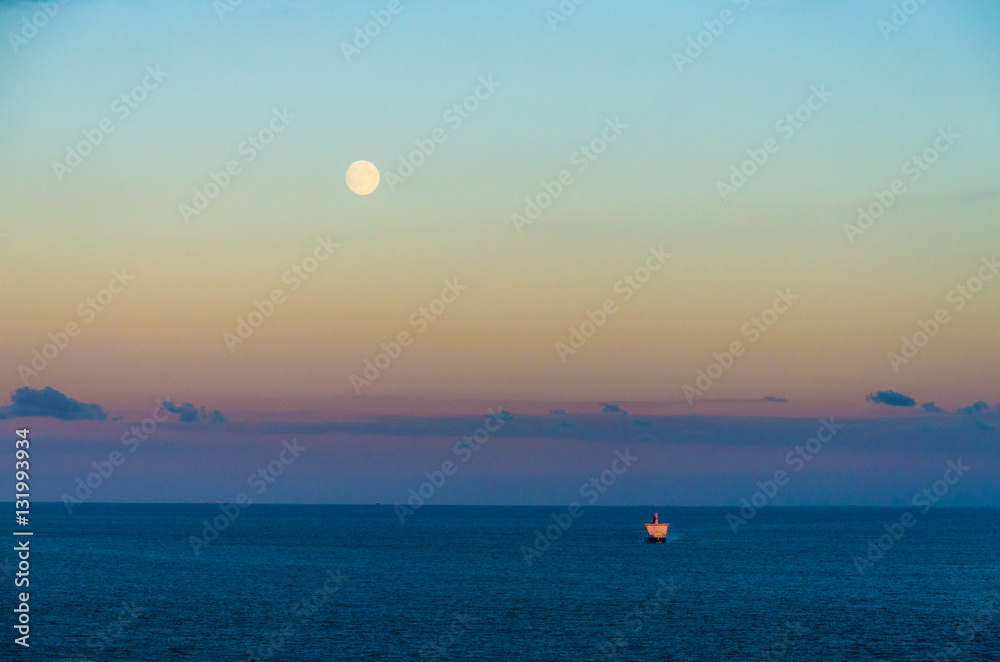 A ferry crossing the English Channel from Dover under a full moon at sunset, England A ferry crossing the English Channel from Dover under a full moon at sunset, England