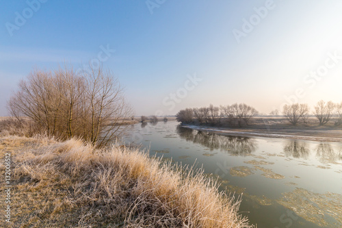 Winter scenery, with frozen river and frost cover vegetation on a cold, sunny, day
