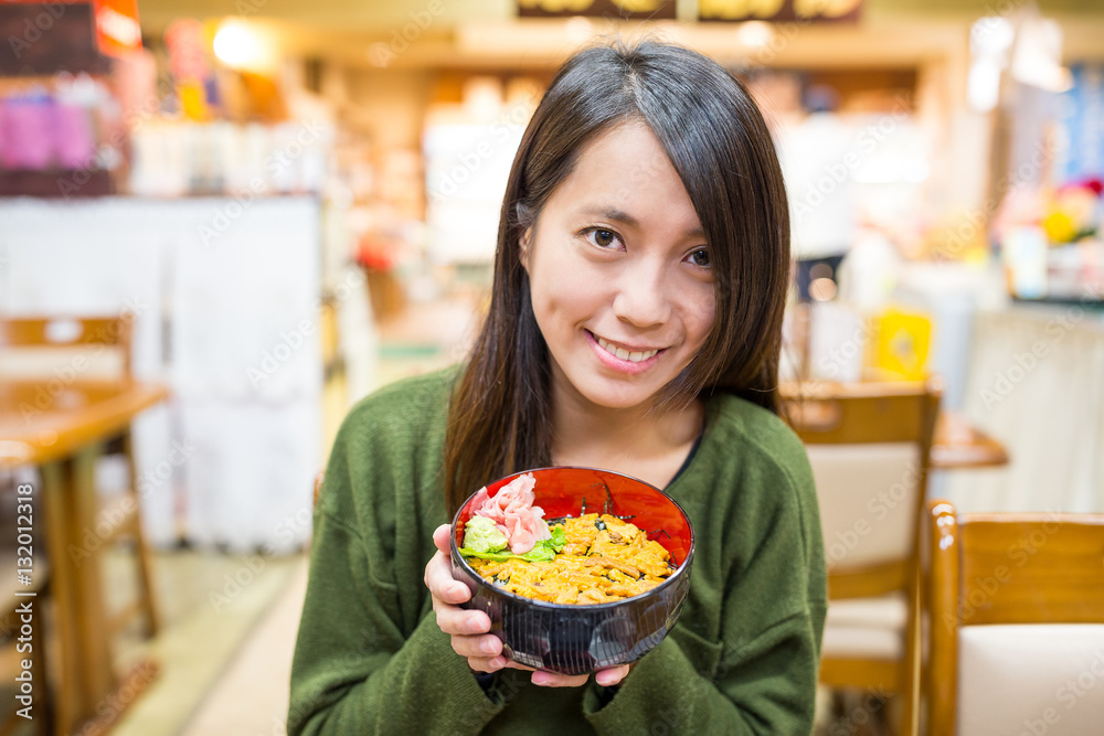 Woman enjoy urchin rice bowl in Japanese restaurant