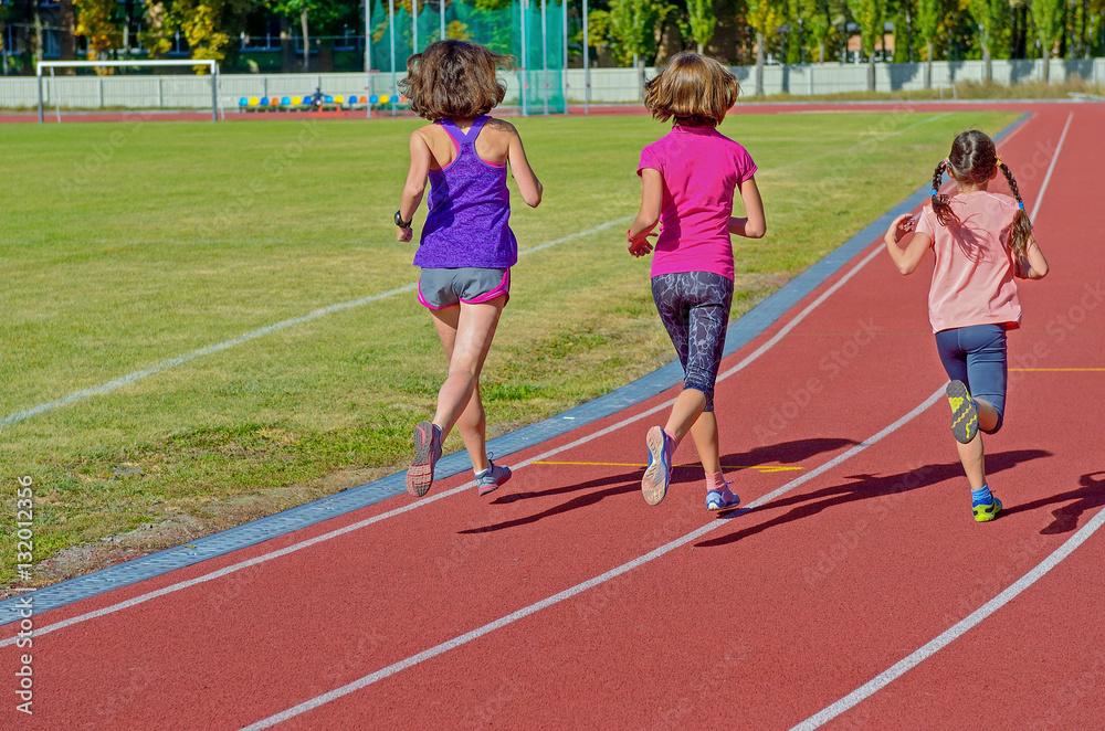 Family fitness, active mother and kids running on stadium track, back view, training with children sport concept
