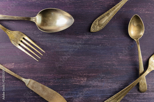 Vintage forks, knife, and spoons, forming frame on purple