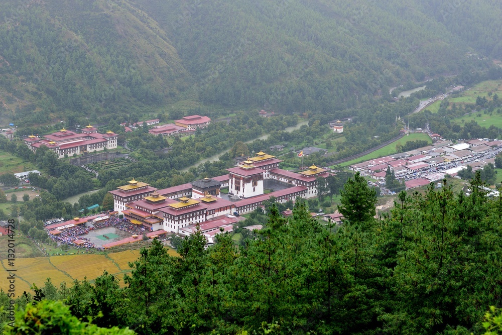 View of Tashichho Dzong (Thimphu Fort) shot along the Wangditse nature trail in Thimphu, Bhutan. Crowds have gathered in the rear courtyard to watch the annual religious festival, the tsechu.