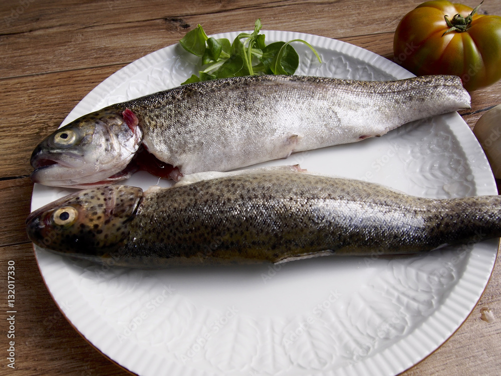 Two raw trout in a plate